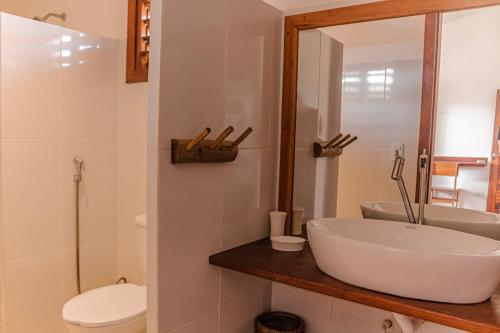 a bathroom with a sink and a toilet and a mirror at Vila Tao in Fortim