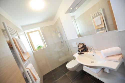 a white bathroom with a sink and a shower at Suvendes Apartments in Prato allo Stelvio