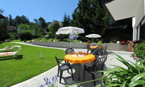 a table with chairs and an umbrella in a garden at Suvendes Apartments in Prato allo Stelvio