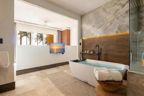 a bathroom with a tub and a tv on a wall at Exclusive Oceanfront Apartment Beach access in Acapulco