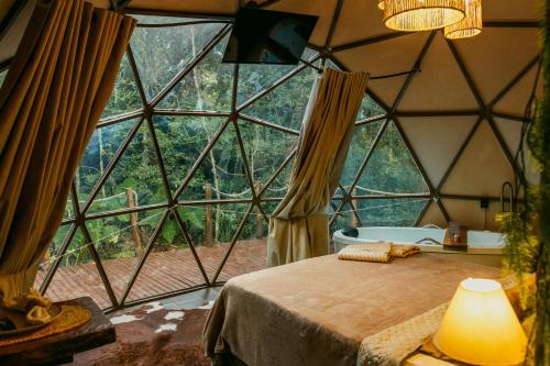 a room with a large glass window with a bed and a tub at Cabana winchesters - Domo in Cascavel