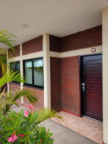 a brick house with a black door and plants at Hotel la Palapa Mazatlan in Mazatlán