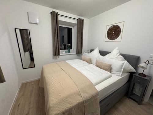a bedroom with a bed with white sheets and a mirror at Liya Apartments in Aiterhofen