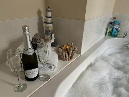 a bath tub with a bottle of wine and two glasses at Chapel St Apartments in Caernarfon