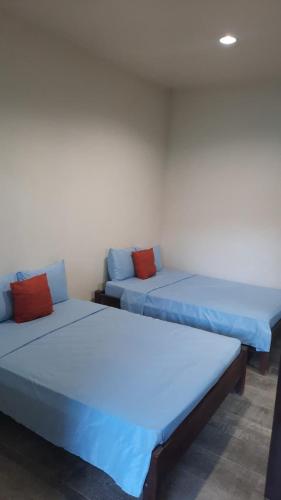 two beds in a room with blue and red pillows at Laguna Hostal Ocean Beach in San Rafael del Sur