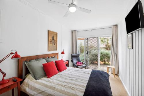 a bedroom with a bed with red pillows and a window at Moonah on Mawson in Anglesea