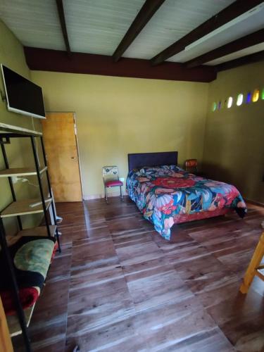 a bedroom with a bed and a wooden floor at Casa Terra Monoambiente in El Bolsón