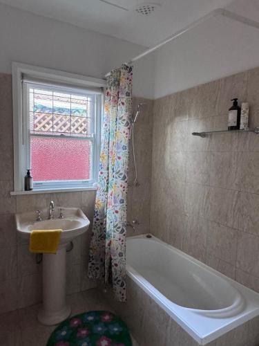 a bathroom with a sink and a bath tub and a window at Ocean Breeze Cottage in Umina