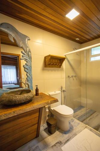 a bathroom with a toilet and a glass shower at Grajagan Surf Resort in Ilha do Mel