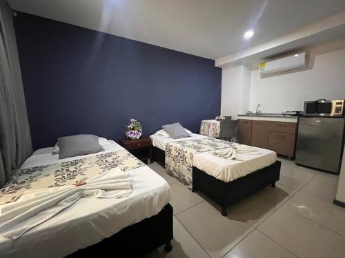 a hotel room with two beds and a kitchen at Apartaestudio con cocina dentro centro comercial in Cartago