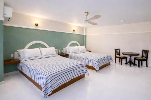 two beds in a room with a table and chairs at Blue Pacific Suites in Mazatlán