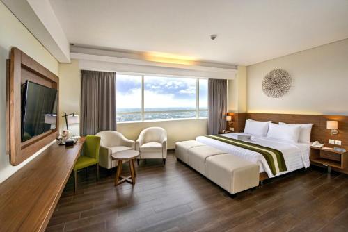 ジャカルタにあるGrand Whiz Poins Simatupang Jakartaの大きなベッドと大きな窓が備わるホテルルームです。