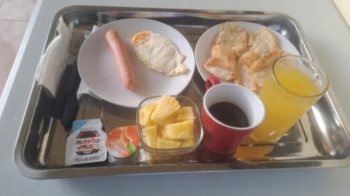 a tray of food with breakfast foods and a glass of orange juice at Habitación Taina in Jarabacoa