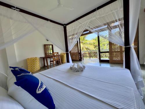a bedroom with a large white bed with two pillows at CoCo-SuRf-House, Luxury among palms in Hikkaduwa