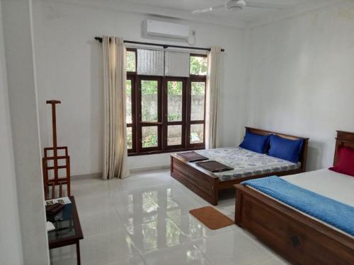 a bedroom with a bed and a couch and a window at Bosadi Hotel katunayake in Katunayaka