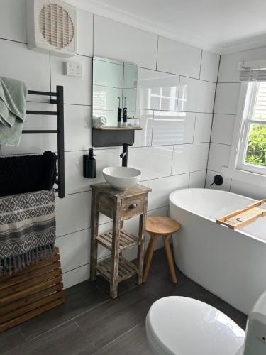 a white bathroom with a tub and a sink at The Artists Cottage Waterfront Hideaway in Strahan