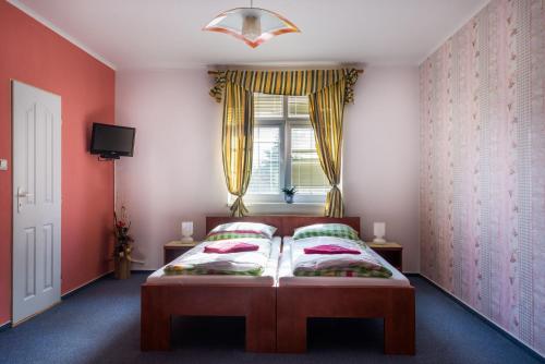 チェスカー・リーパにあるPenzion Na Kopečkuのベッドルーム1室(赤い壁のベッド1台、窓付)