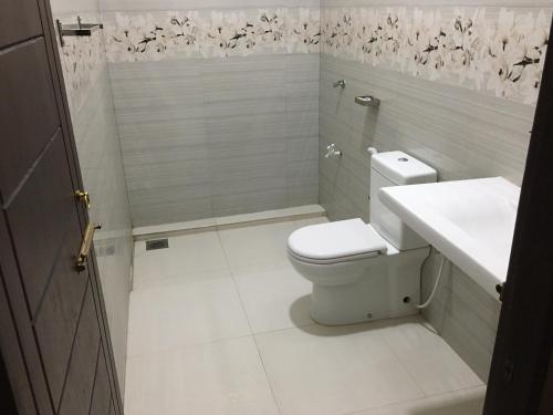 a white bathroom with a toilet and a sink at Bosadi Hotel katunayake in Katunayaka