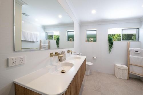 a white bathroom with a sink and a mirror at Broadwater Breeze in Airlie Beach