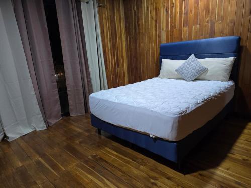 a bed with a blue headboard in a room at Casa Las Brisas in Nicoya