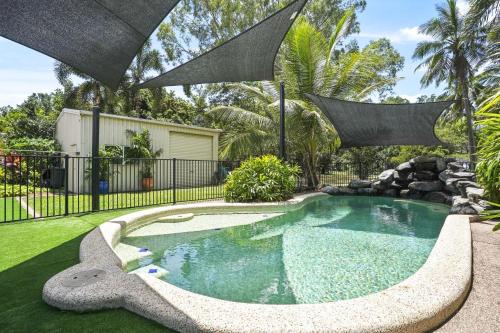 a swimming pool in a yard with an umbrella at Beachfront Serenity Family Home at Wonga Beach in Wonga