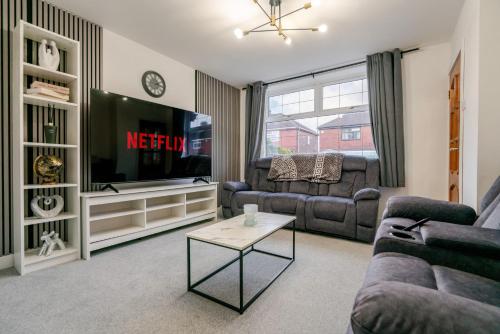 a living room with a couch and a tv at Spacious 4 bed Ideal for Business & Long Term Stays, Free Parking in Manchester