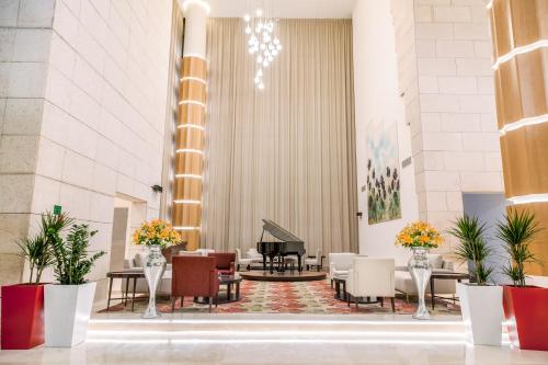 a lobby with a piano and chairs and tables at Mövenpick Hotel Amman in Amman
