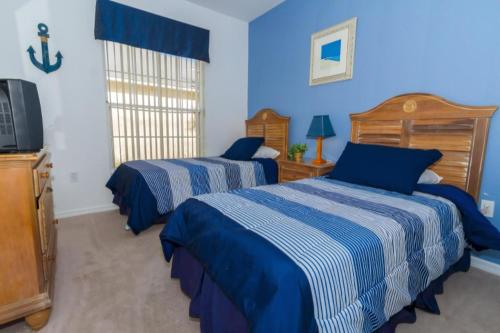 two beds in a bedroom with blue walls and a tv at Home With A View! in Orlando