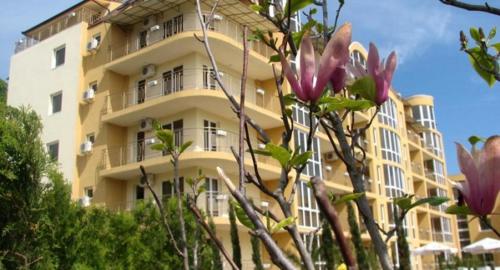 a yellow building with a tree in front of it at Elias Apartment in Golden Sands