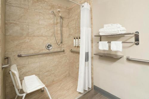 a bathroom with a shower with a white chair at City Express by Marriott Danville in Danville
