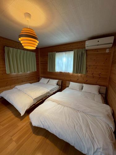 ein Schlafzimmer mit zwei Betten und einem Kronleuchter in der Unterkunft 最大4名の城ノ浜プール近くの宿 in Kihokucho