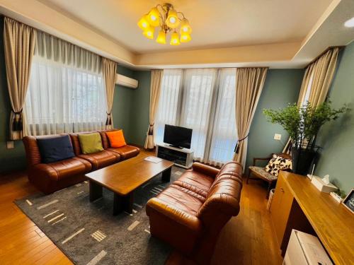 a living room with leather couches and a television at ユーカラ屋 in Nanae