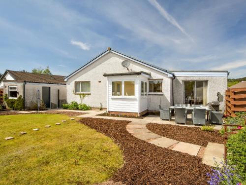 a white house with a patio and a yard at Westburn in Comrie