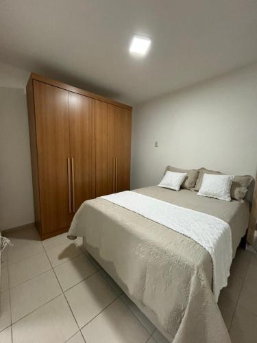 a bedroom with a large bed and a wooden cabinet at Cantinho da Aruana, conforto e tranquilidade in Aracaju