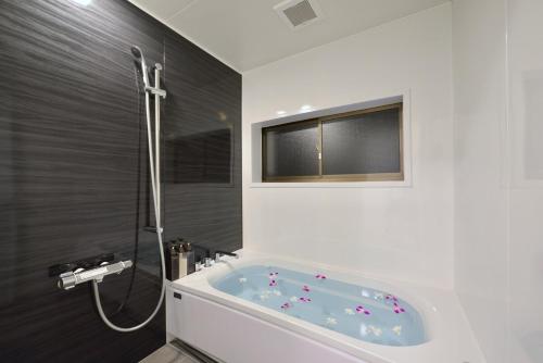 a bathroom with a bath tub and a window at 064Villa 美海璃 in Nanjo
