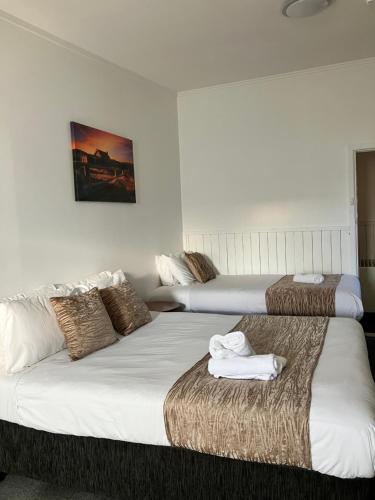 two beds in a hotel room with towels on them at Berridale Inn in Berridale