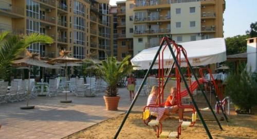 two children sitting on a swing at a resort at Elias Apartment in Golden Sands