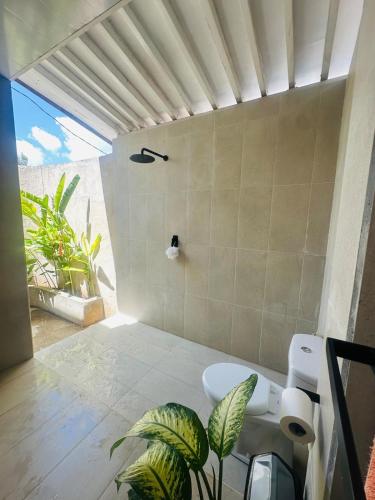 a bathroom with a shower with a toilet and plants at Twin Palms Rote in Nembrala