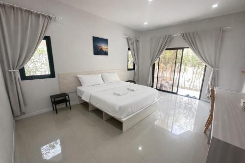 a bedroom with a bed with white sheets and windows at Rayong Valley Resort in Ban Khao Chak Khaek (1)