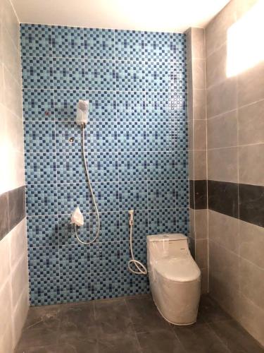 a bathroom with a toilet and a blue tiled wall at Tổ Nhím Homestay in Ấp Cái Chuối