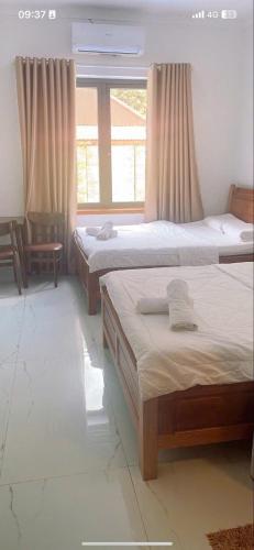 a bedroom with two beds and a window at Khách sạn Kiến Đức in Kiến Ðức