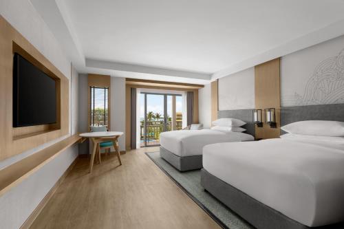 a hotel room with two beds and a flat screen tv at Phuket Marriott Resort & Spa, Merlin Beach in Patong Beach