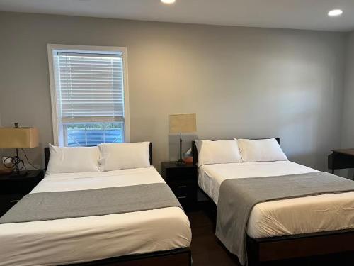 two beds in a room with a window at 25 Lux Room 5 - 2 Queen Beds, Shared Bathroom - Nonsmoking in Arlington