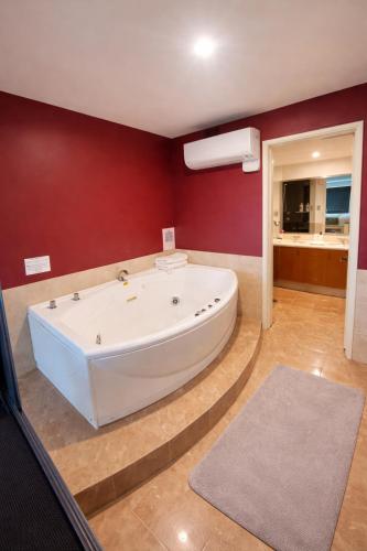 a large white tub in a room with red walls at Ocean View-breath Taking Views, Amazing Facilities in Perth