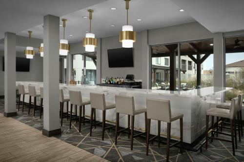 a restaurant with a bar with white chairs at Courtyard by Marriott Waco in Waco