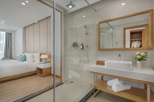 a bathroom with a bed and a sink and a shower at TMS Hotel Da Nang Beach in Danang