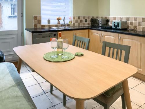 a kitchen with a wooden table with wine glasses on it at Paddy's Cottage in Flookburgh