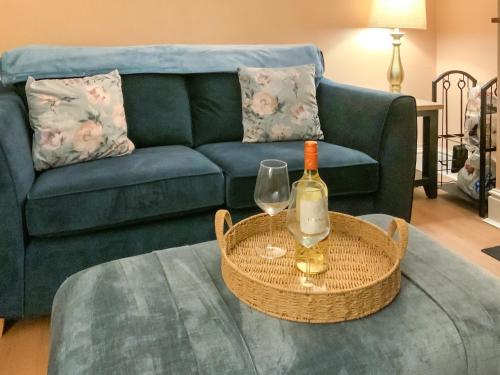 a living room with a couch and a table with a bottle of wine at Paddy's Cottage in Flookburgh