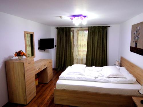 a bedroom with a bed and a dresser and a mirror at Pensiunea Casa Zarnesteana in Zărneşti