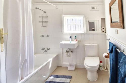 a white bathroom with a tub and a toilet and a sink at A Warm & Charming Retreat in Castlemaine